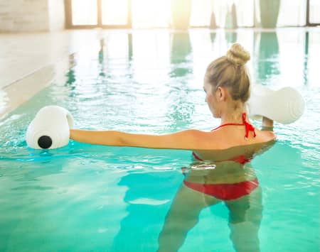 pensioners doing hydro therapy exercises with pool noodles